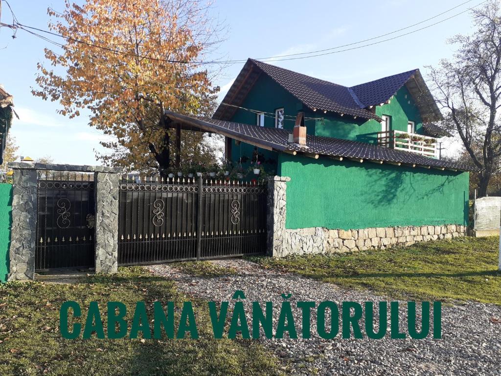 ein Haus mit einem Tor davor in der Unterkunft Cabana Vânătorului 