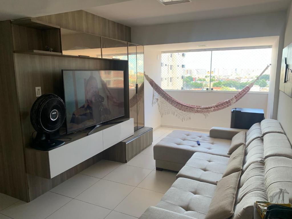 uma sala de estar com uma televisão de ecrã plano e um sofá em Apartamento 3 quartos equipado em Maceió