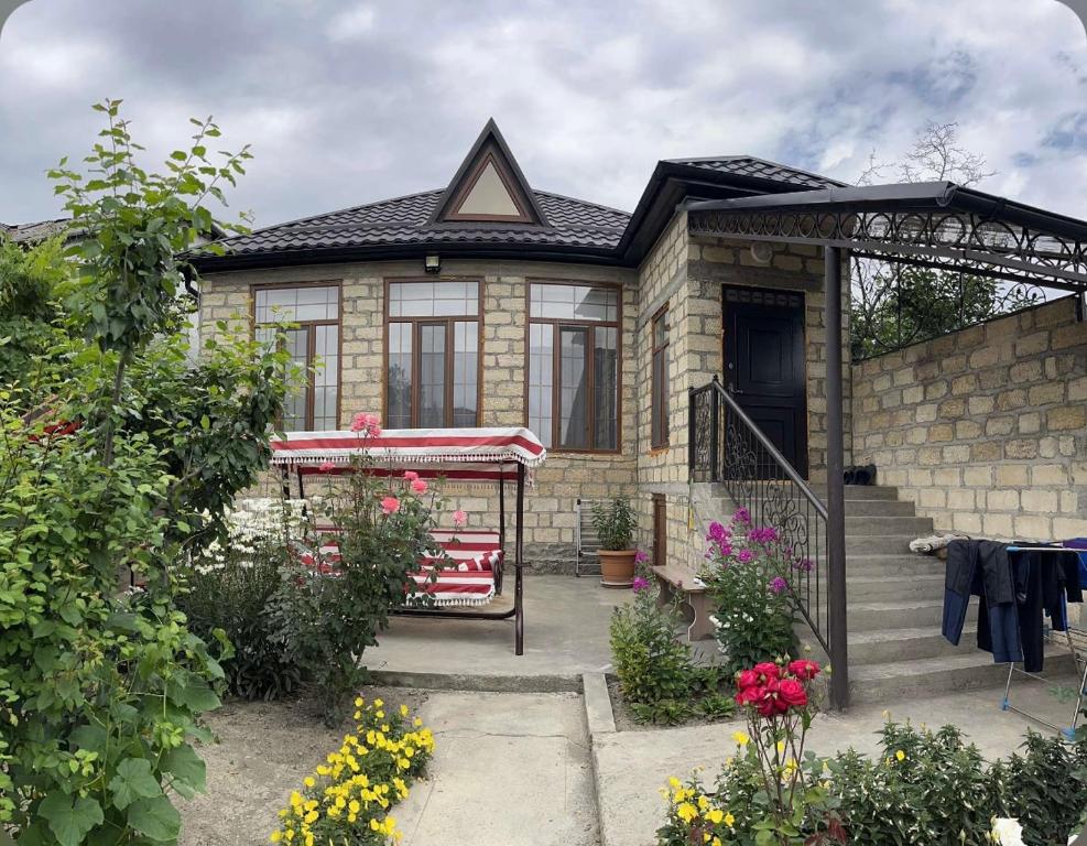 a brick house with a porch and some flowers at Halal House VİP in Qusar