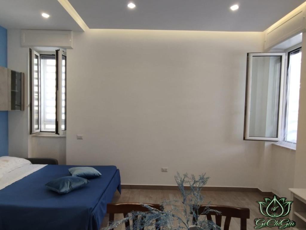 una camera da letto con un letto con lenzuola blu e due finestre di Al GeChiGiù a Bacoli