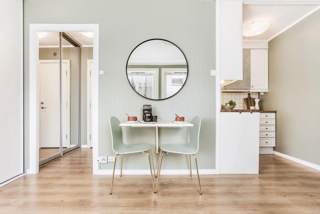 a dining room with a table and chairs and a mirror at Charming studio apartment in Bergen