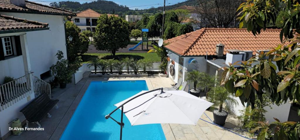 a swimming pool with an umbrella next to a house at Casa da Venda in Ponte de Lima