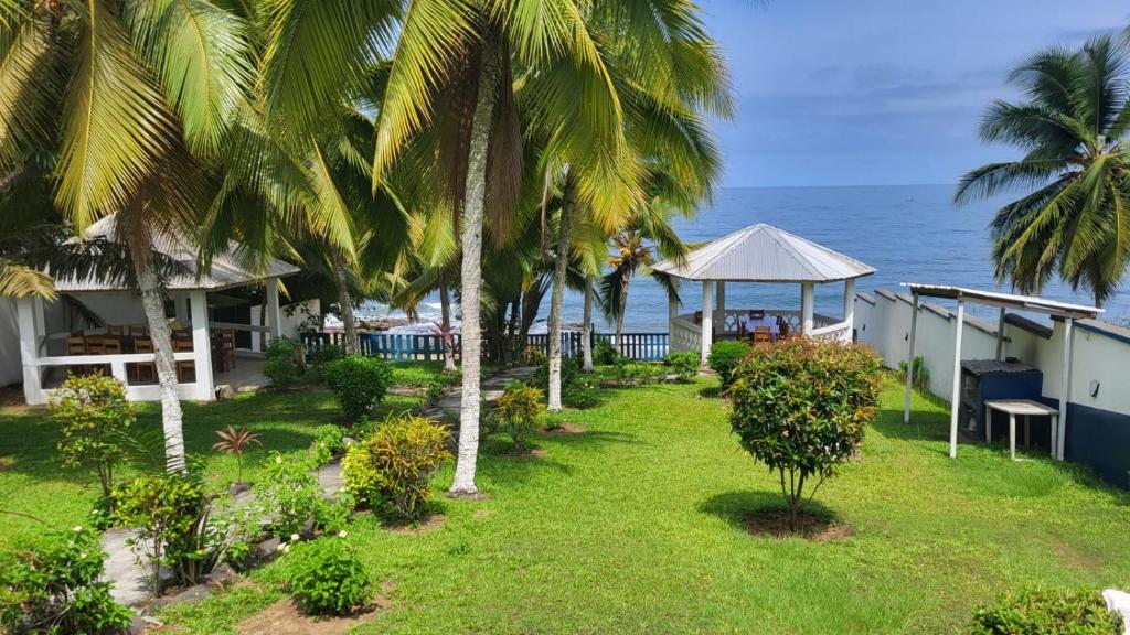 un patio del complejo con palmeras y el océano en Résidence Callens, en Kribi
