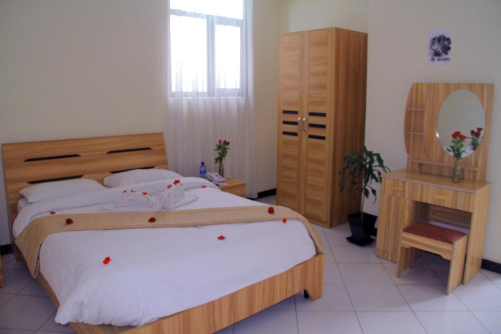 1 dormitorio con 1 cama grande y espejo en Ekshesh Hotel Bishoftu en Debre Zeyit