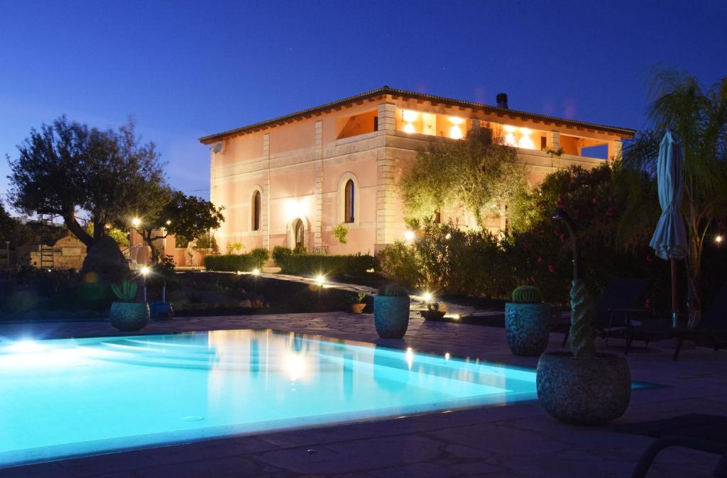 een villa met een zwembad voor een gebouw bij Antico Casale Benalì in Siracusa