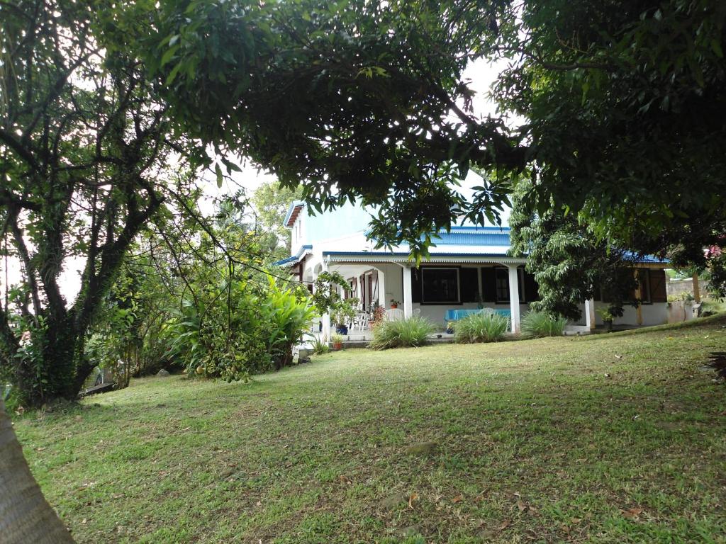 a house with a blue roof and a yard at Appartement Les Bougainvilliers Vue Mer in Saint-Claude