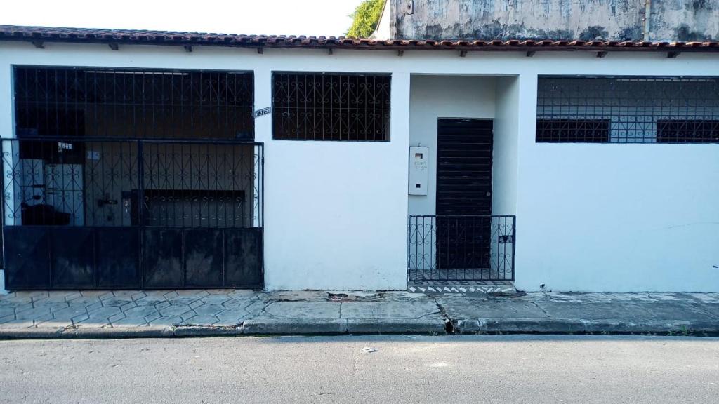 un edificio blanco con una puerta y una valla en 7 camas de casal - Casa próxima ao Bumbódromo, en Parintins