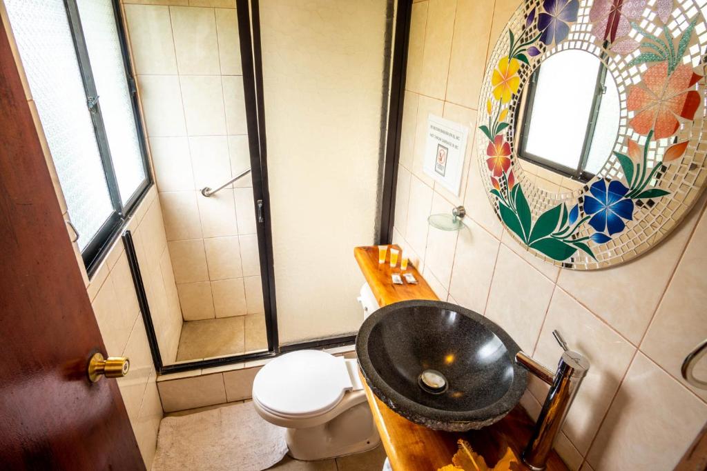 uma casa de banho com um lavatório, um WC e um espelho. em Hotel Chez Maria Goretti em Hanga Roa