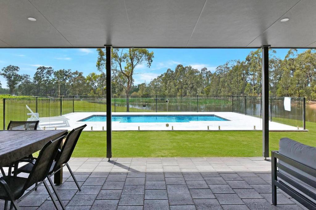 an outdoor patio with a table and a swimming pool at The Lodge - Ironstone Estate Hunter Valley in Lovedale