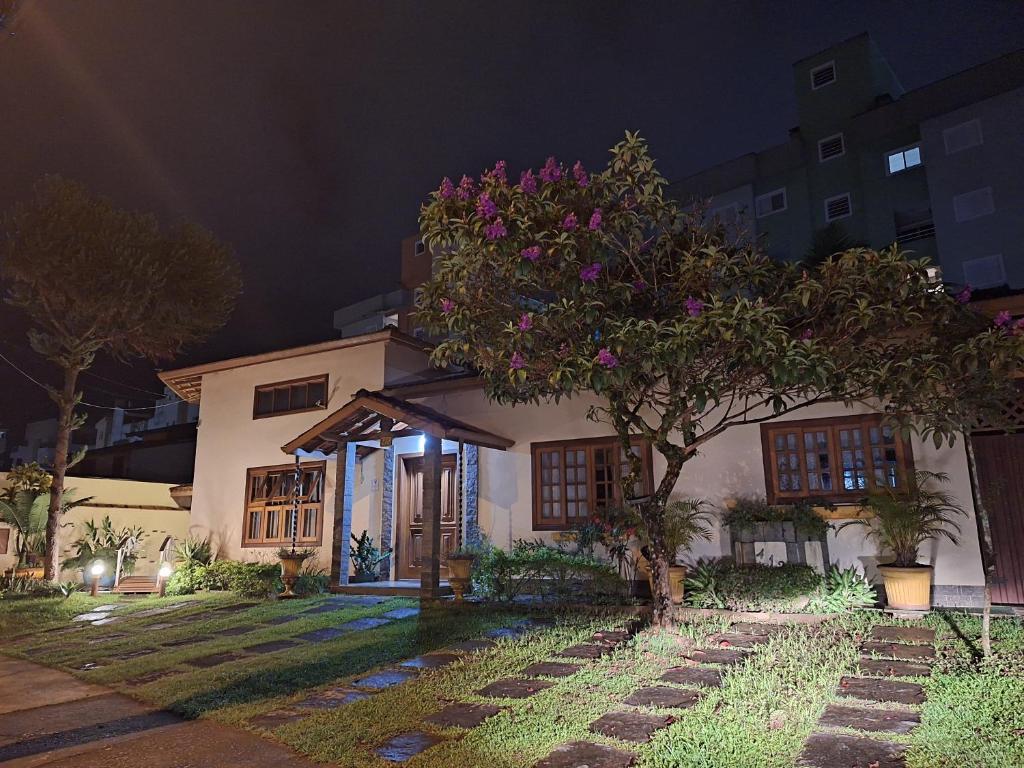 a house with a tree in front of it at night at Suítes Jardim dos Sonhos in Ubatuba