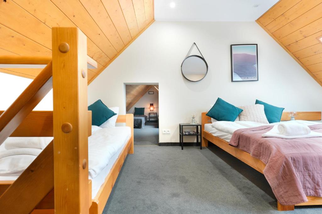 a attic bedroom with two beds and a staircase at Willa Sasanka in Duszniki Zdrój