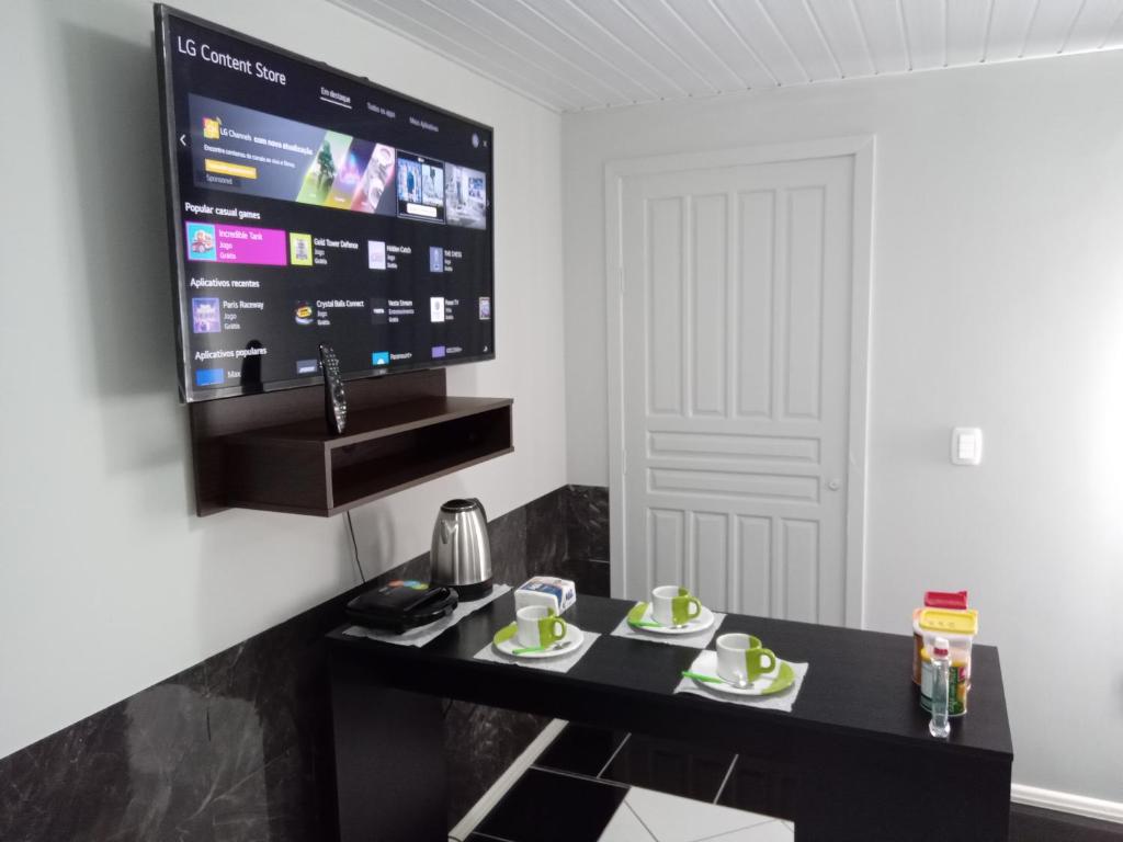 a living room with a black table and a tv at POUSADA ALTERNATIVA MANU LAGES suite in Lages