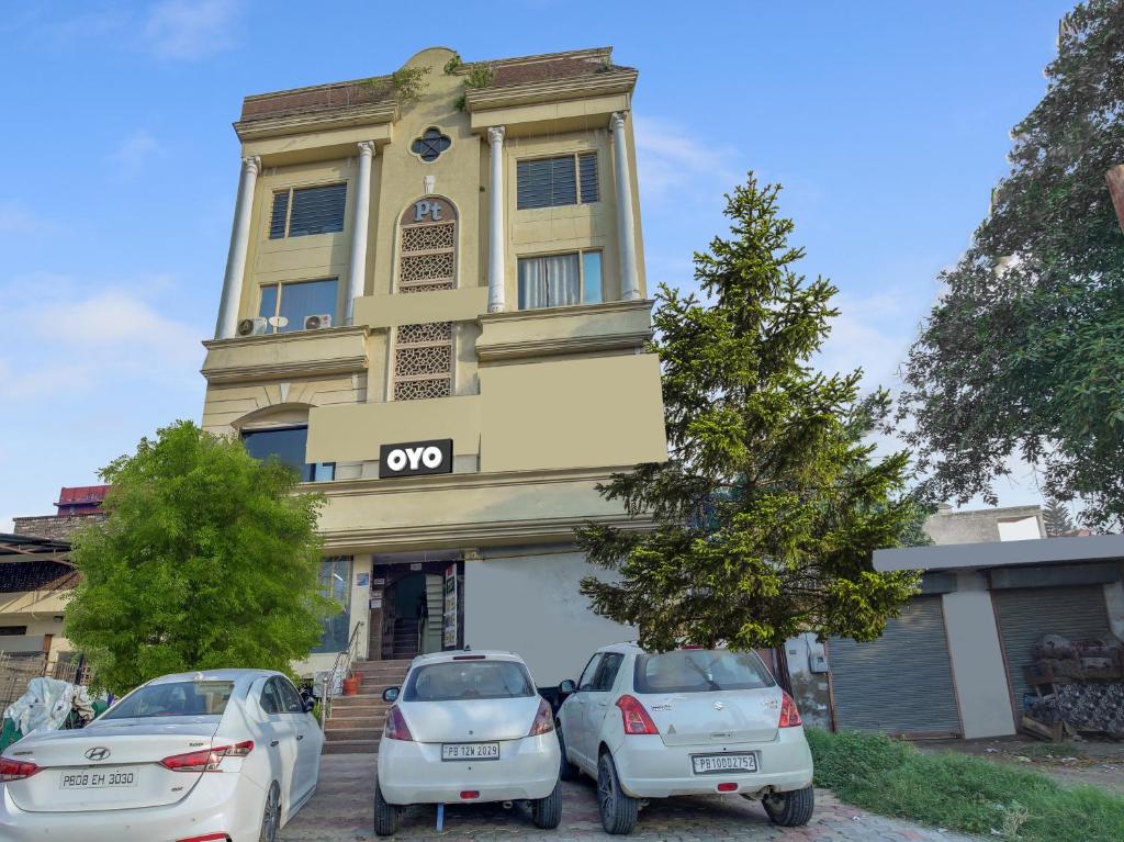 two cars parked in front of a building at Super OYO Collection O Hotel White Prime in Phagwāra