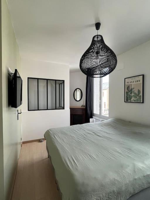 a bedroom with a large bed and a chandelier at Charmante maison de ville in Bourges