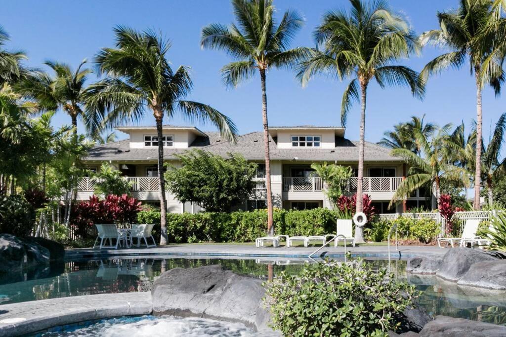 a resort with a swimming pool and palm trees at Five Star Waikoloa Beach Villa, Golf & Lake Views in Waikoloa