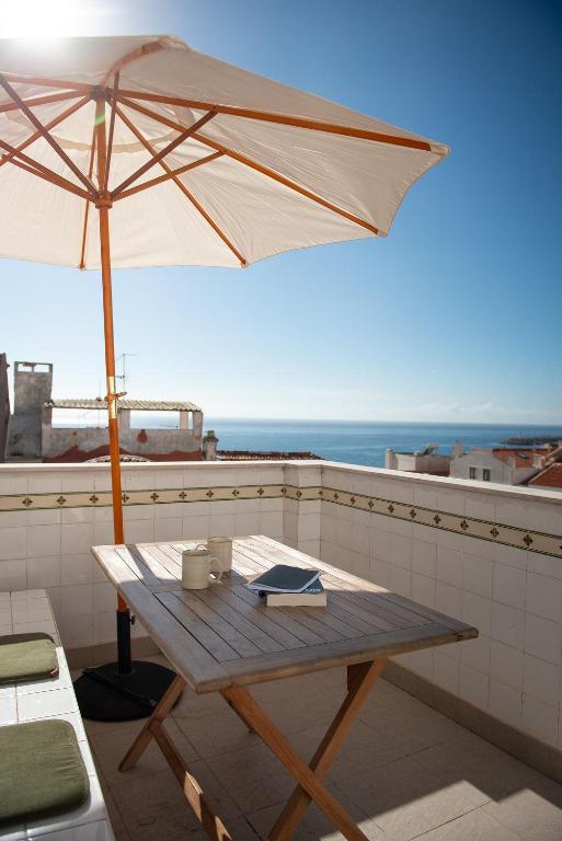 a wooden table with an umbrella on a balcony at Private Terrace Refúgio in Sesimbra