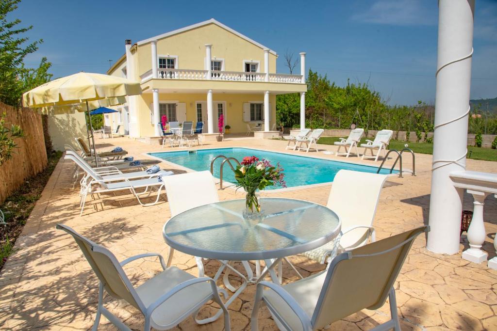 um pátio com uma mesa e cadeiras e uma piscina em Villa Martini em Vátos