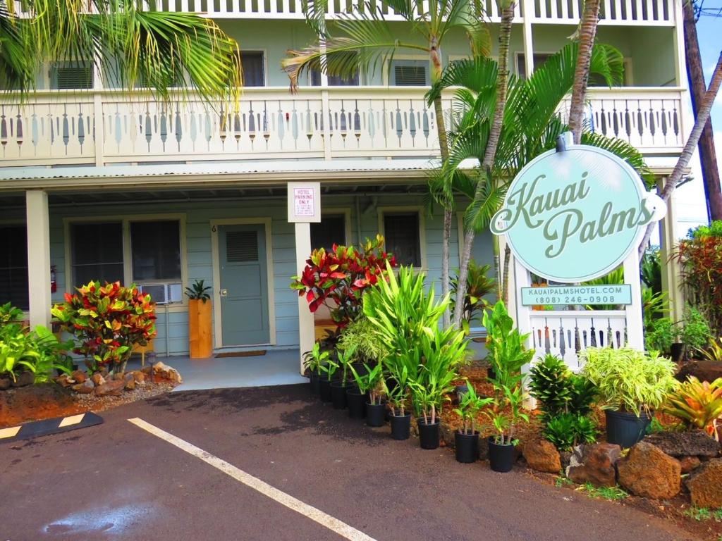 a sign in front of a building with plants at Kauai Palms Hotel in Lihue