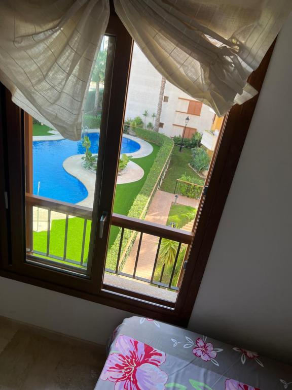 een slaapkamer met een raam met uitzicht op een zwembad bij Apartment in Punta Prima (Torrevieja) 200m to Sea in Punta Prima