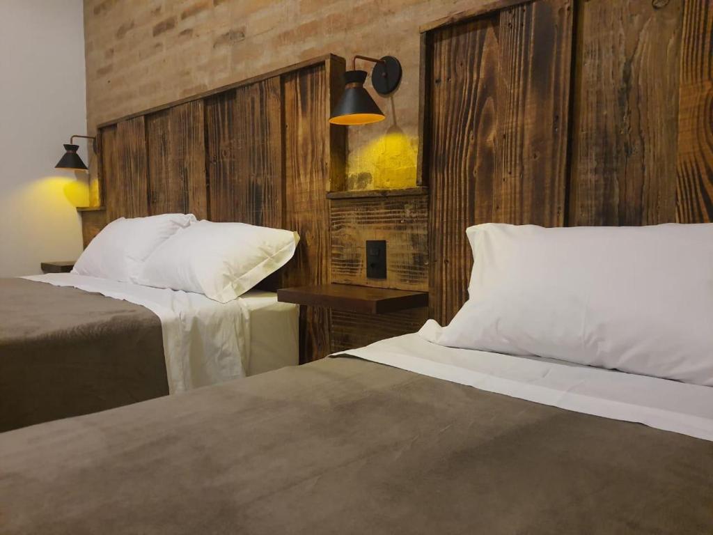 1 dormitorio con 2 camas y pared de madera en Suítes Capitólio Canastra en Capitólio