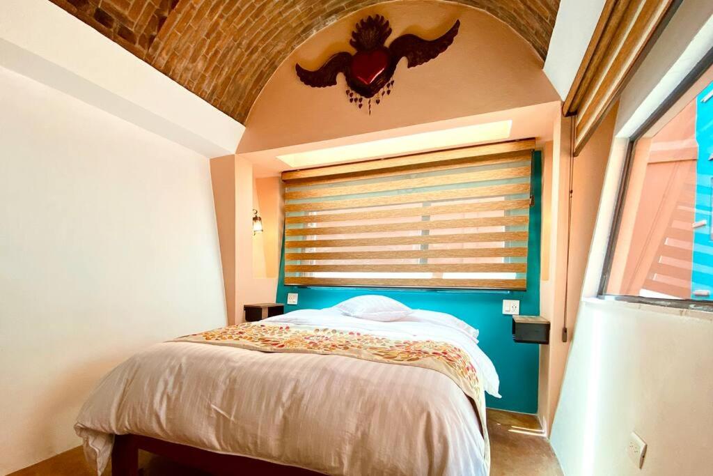 a bedroom with a bed and a window with a bat on the wall at Casa La Luz #2 Private One- bedroom Apartment with Full Kitchen and Private Roof Terrace in San Miguel de Allende