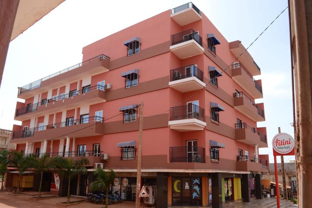 ein rosafarbenes Gebäude auf einer Straße mit einem Stoppschild in der Unterkunft Résidence GESAM in Sabalibougou