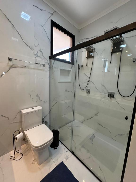 a bathroom with a toilet and a glass shower at Casa para Agrishow in Ribeirão Preto