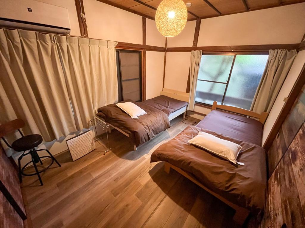 a room with two beds and a chandelier at 温泉街の入り口にあるゲストハウス SLOW HOUSE yugawara in Yugawara