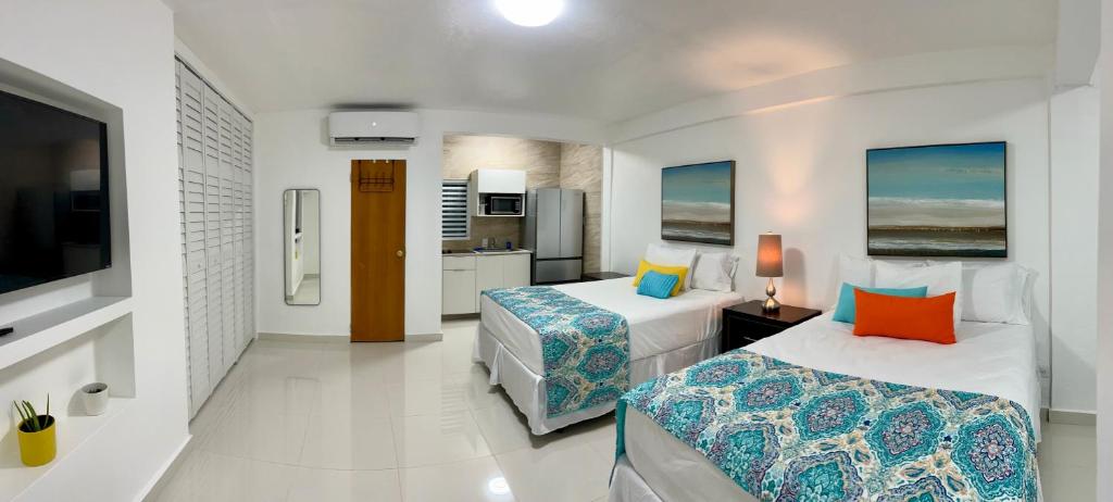 um quarto de hotel com duas camas e uma cozinha em Posada Centric Studio Isla Verde em San Juan