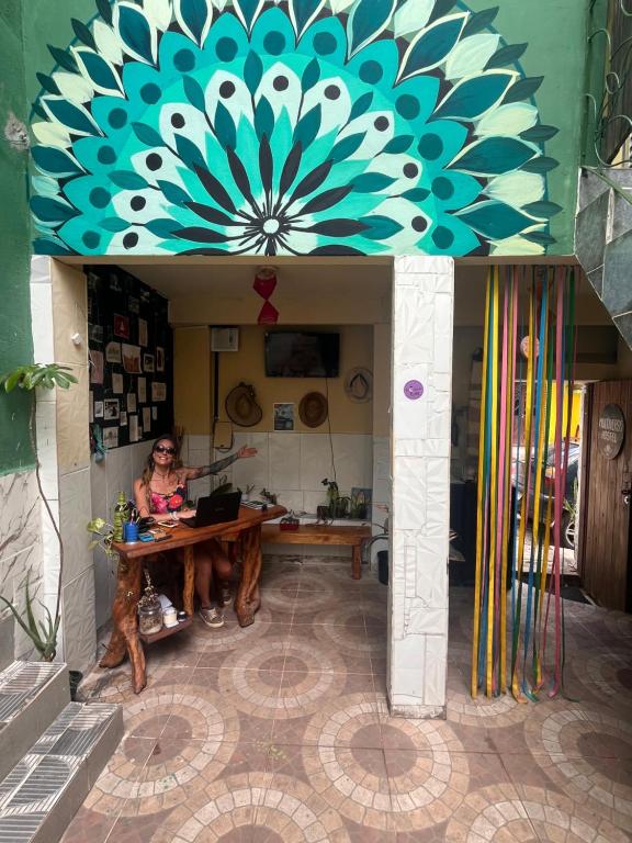 a woman sitting at a table in a room at Multiverso Hostel in Lençóis