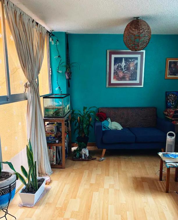 a living room with a blue couch and a fish tank at Bonita y Céntrica habitación con sofa cama in Mexico City