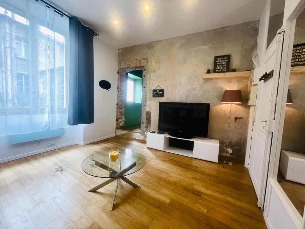 un salon avec une télévision et une table en verre dans l'établissement Ruby- Quai St Laurent- Bastille, à Grenoble