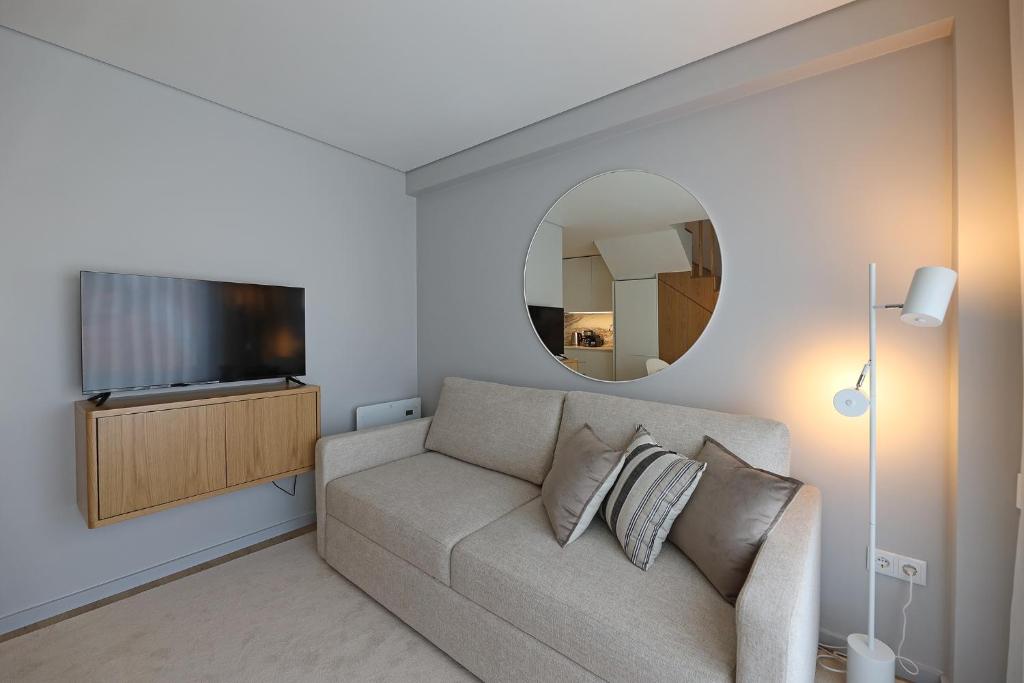 een woonkamer met een bank en een spiegel bij FLH Boavista Woody Duplexes in Porto