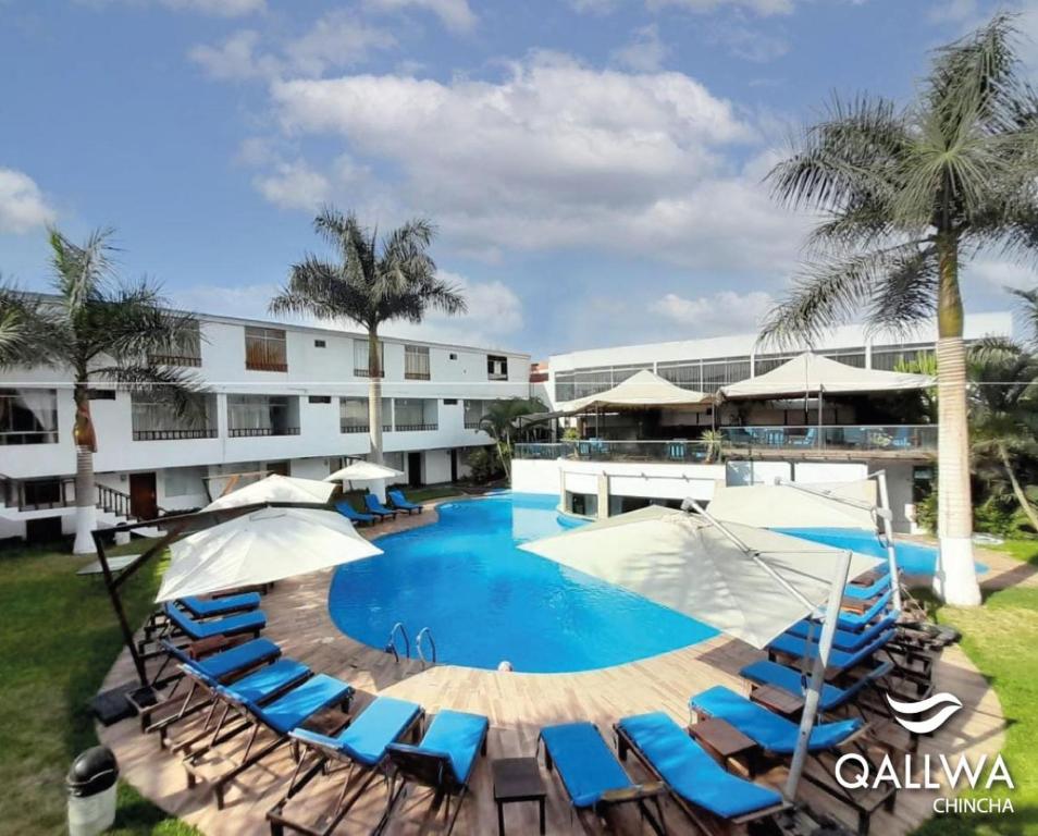 a resort with a swimming pool with chairs and umbrellas at Qallwa Chincha in Chincha Alta