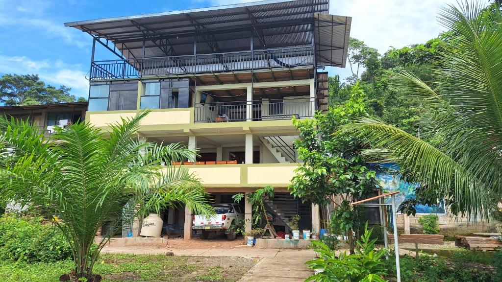 a yellow building with a balcony and palm trees at Oropendola Lodge Manu in Pillcopata