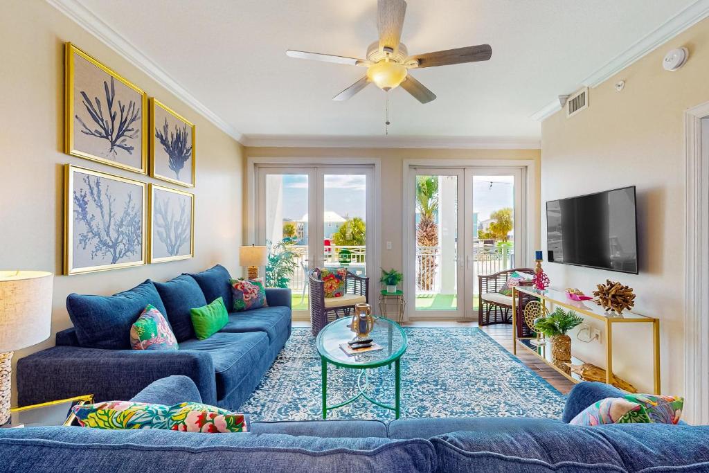 sala de estar con sofás azules y TV en Tranquil Harbour 103: Casa Del Mar, en Mexico Beach