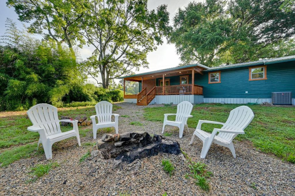 a group of chairs sitting around a campfire in front of a house at Charming Eagletown Home with Deck and Private Hot Tub! in Eagletown