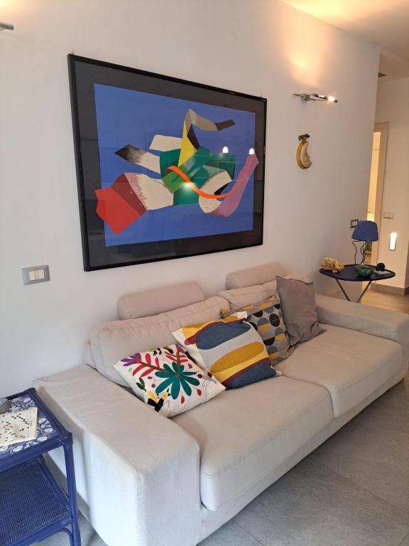 a living room with a white couch with a painting on the wall at Casa di Rosa al Negombo in Ischia