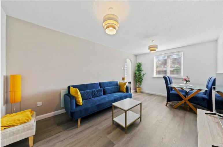 Stylish 2 bedroom Apartment in Kettering Town Centre, sleeps 4, free parking, wifi, Sky, Netflix في نورثامبتون: غرفة معيشة مع أريكة زرقاء وطاولة