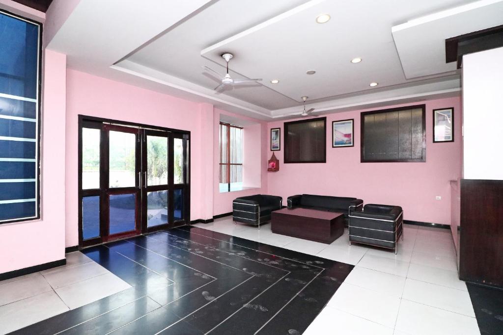uma sala de estar com paredes cor-de-rosa e um sofá em SPOT ON Hotel Center Point em Rāmpura