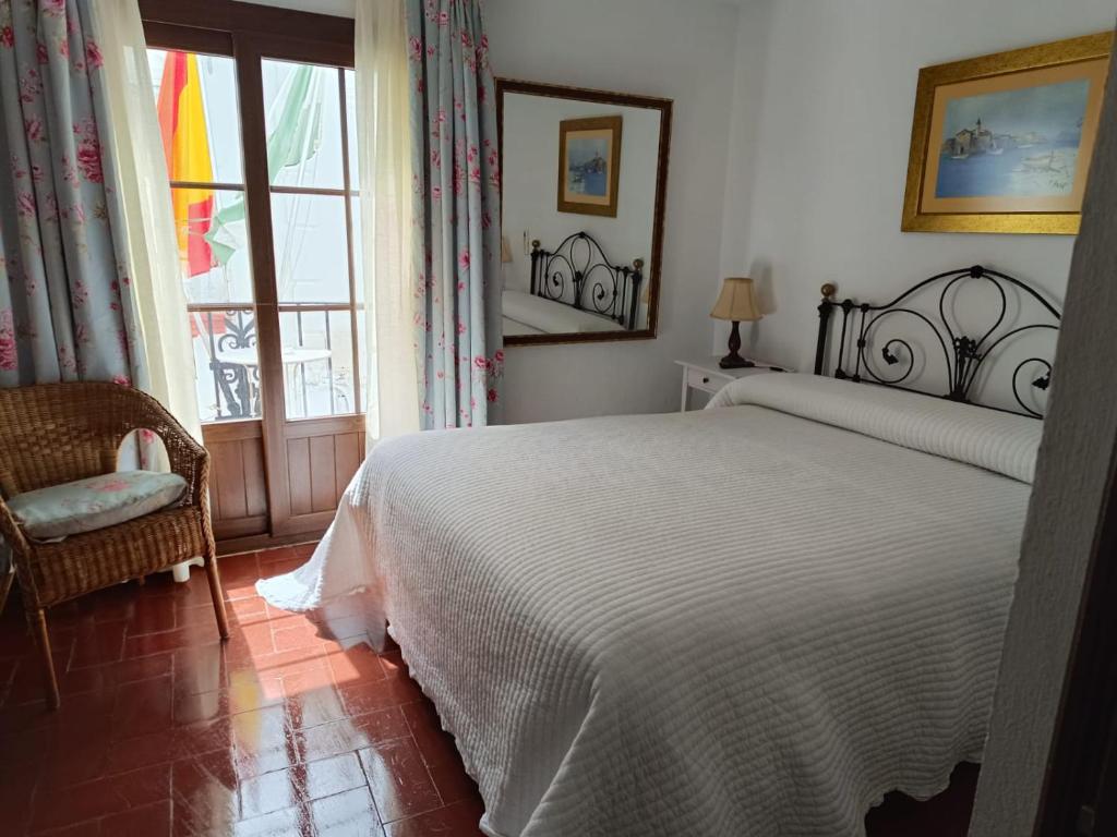 um quarto com uma cama branca e uma janela em Hostal Gran Capitan em Chipiona