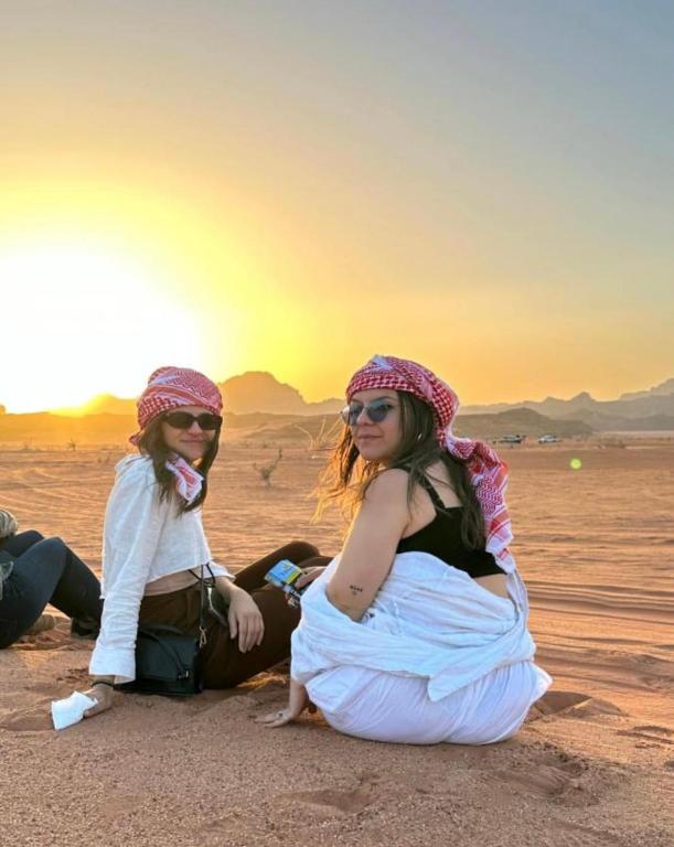 two young women sitting in the desert at sunset at Wadi Rum Heaven Camp in Wadi Rum