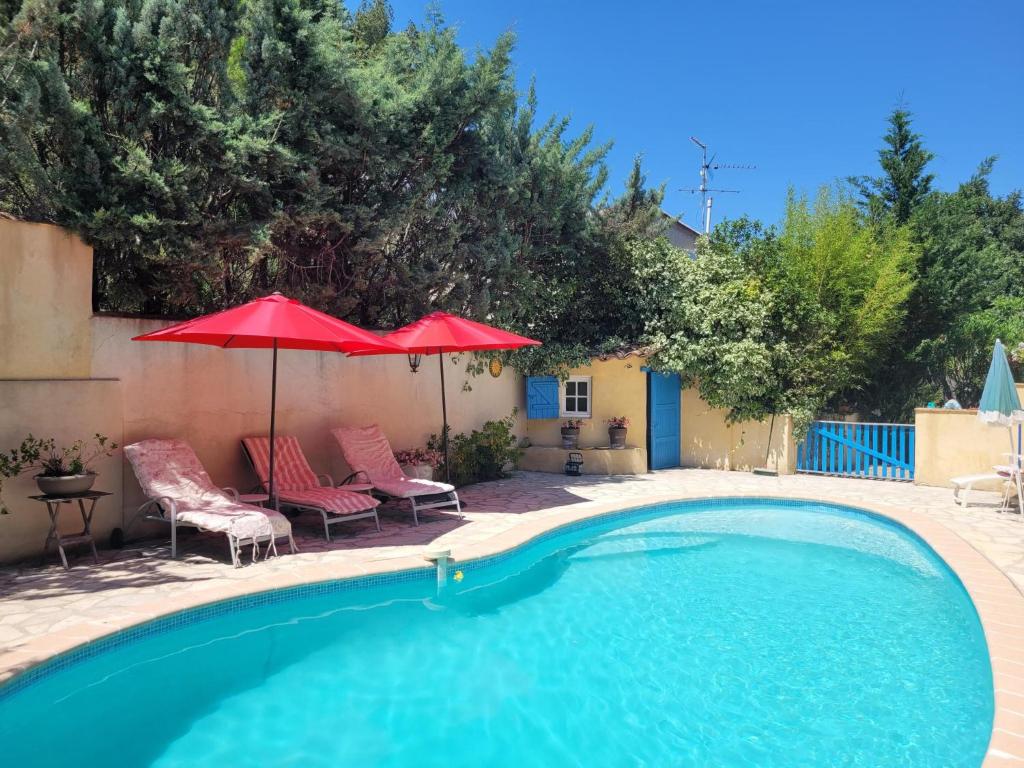 a swimming pool with two chairs and an umbrella at Les Iris in Lorgues