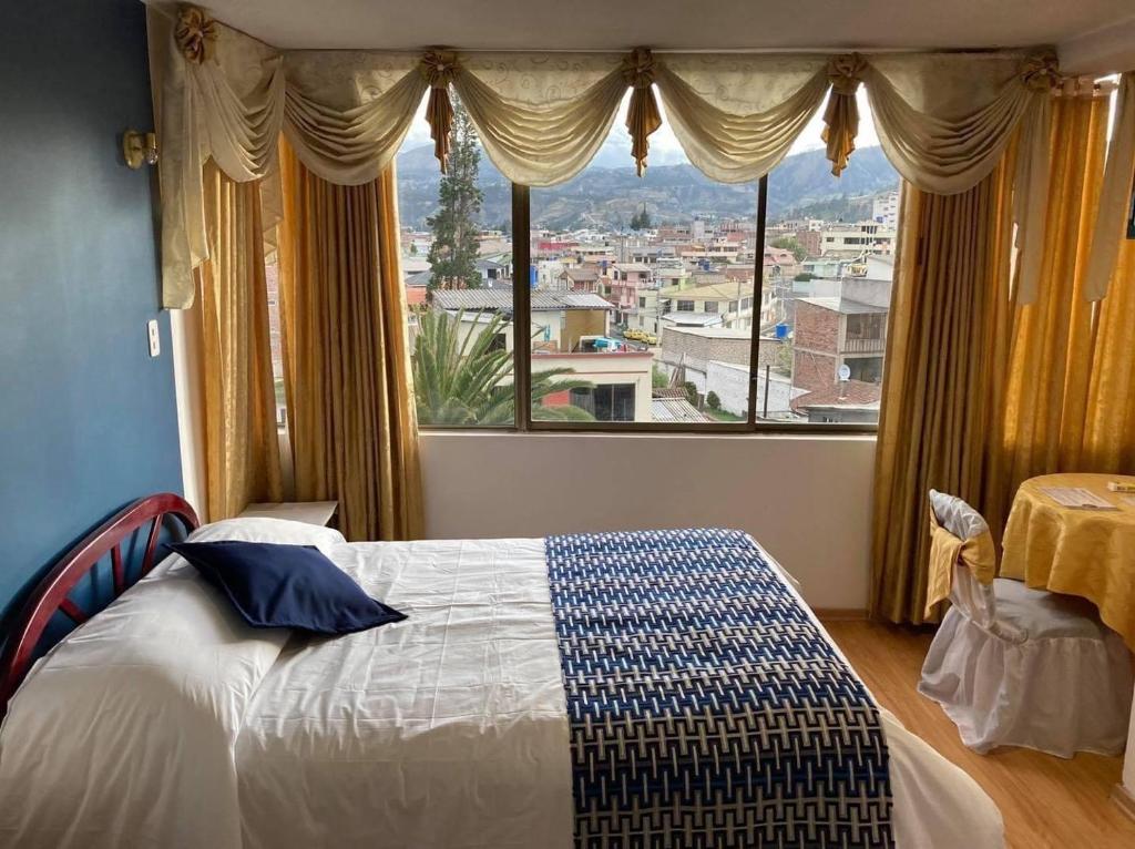 ein Schlafzimmer mit einem Bett und einem großen Fenster in der Unterkunft Hotel El Cisne Internacional in Riobamba