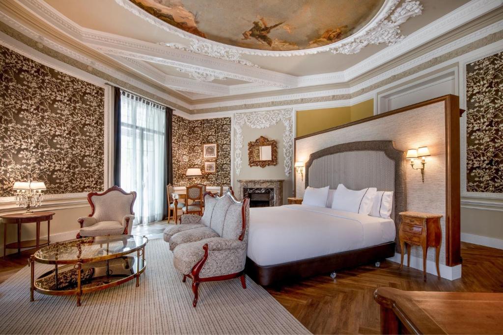 a bedroom with a bed and a couch and a table at Hotel Palacio del Retiro, Autograph Collection in Madrid
