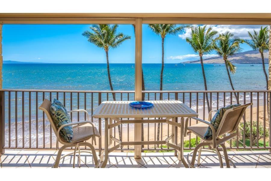 a table and chairs on a balcony with the beach at KIHEI BEACH #504 condo in Kihei