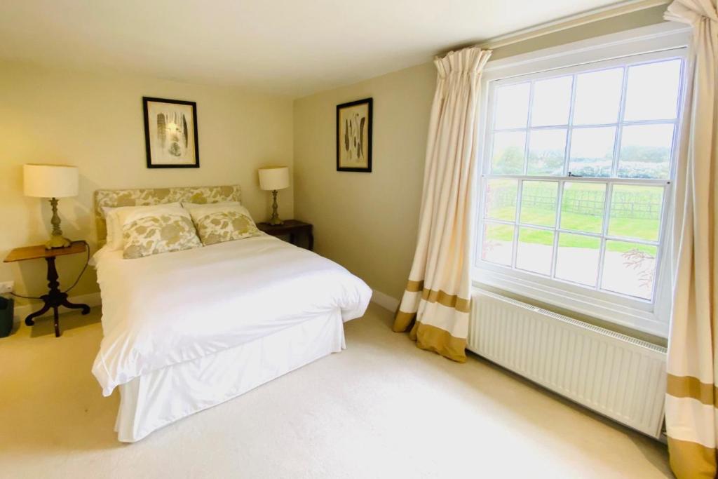 a bedroom with a bed and a large window at Stunning 6-bed country house with heated pool in Headcorn