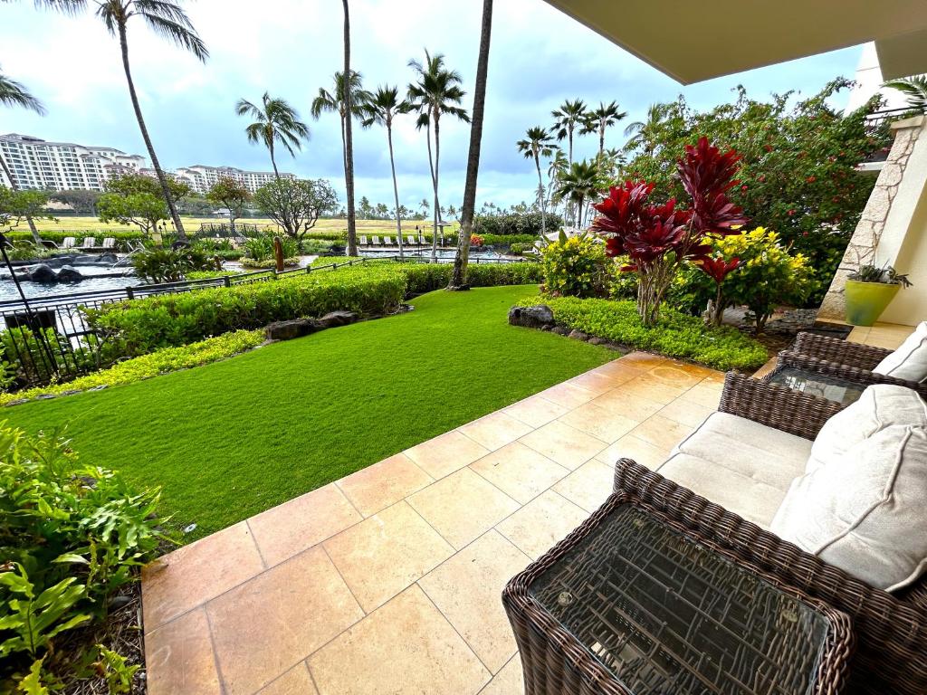 a patio with a lawn with a bench and palm trees at Ground floor unit with Private Garden in Kapolei