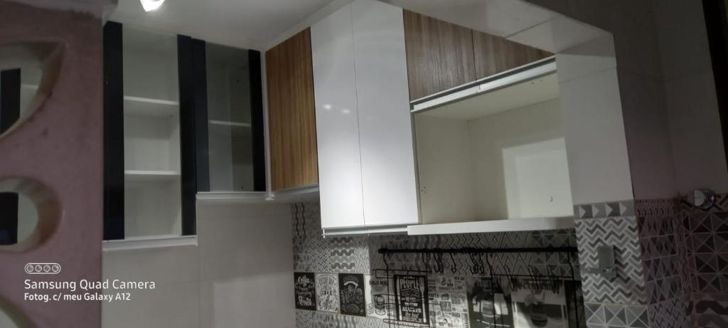 a kitchen with white cabinets and tiles on the wall at Apartamento in Belo Horizonte