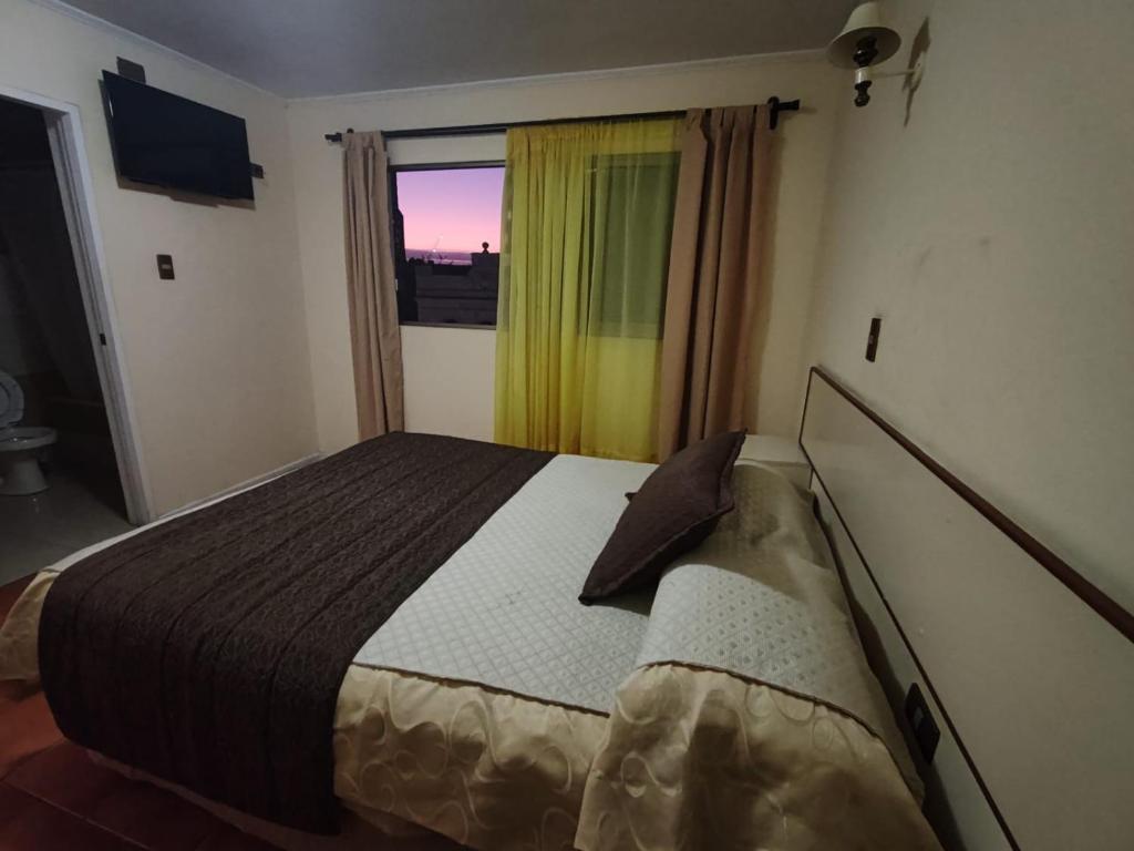 Un dormitorio con una cama grande y una ventana en Hotel Brasil, en Antofagasta